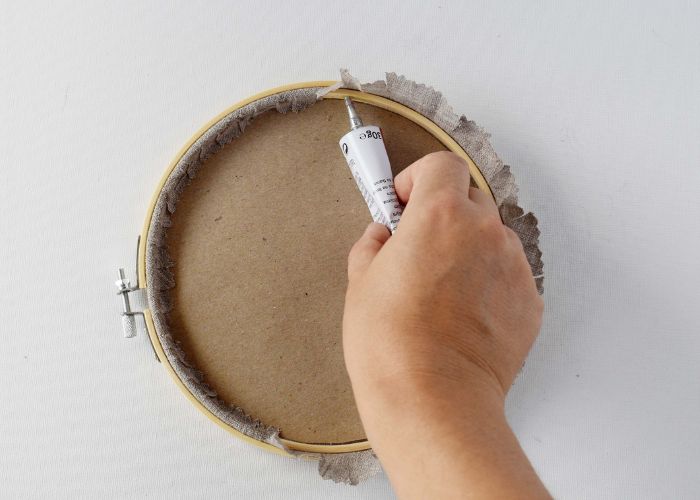 Aufkleben des Randes aus natürlichem Leinenstoff auf den Stickrahmen